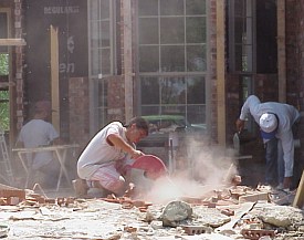 A workman is cutting bricks to use around the windows.