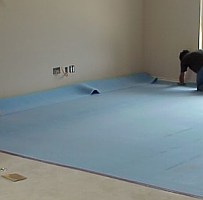 A worker cuts and installs carpet cushion, a layer of padding underneath the carpet.