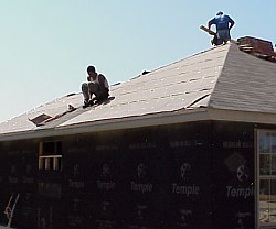 The workers are starting to install  the roofing shingles.