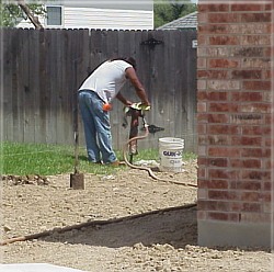 On this property, the worker has to dig through rock to install many of the fence posts.