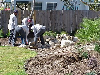 Workers move additional rocks into the landscape.