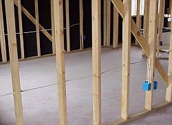 The electrician drills holes to run the wires in the walls to connect to the junction boxes.