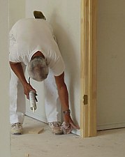 This picture shows a workman applying caulk to seal cracks and holes, creating a smooth surface for painting.