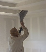 A workman is spraying texture on the interior walls.