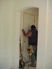 A workman is installing the door on a closet.